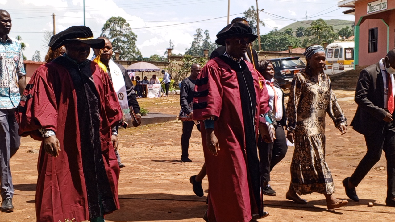 Cortège académique en toge traversant la cour de l'institut lors d'une cérémonie.